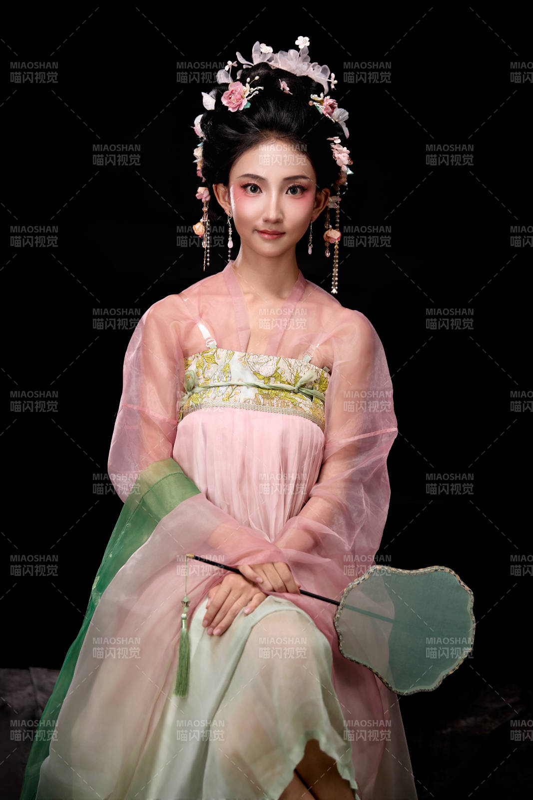 身著唐代簪花仕女服手持輕扇的坐姿女性