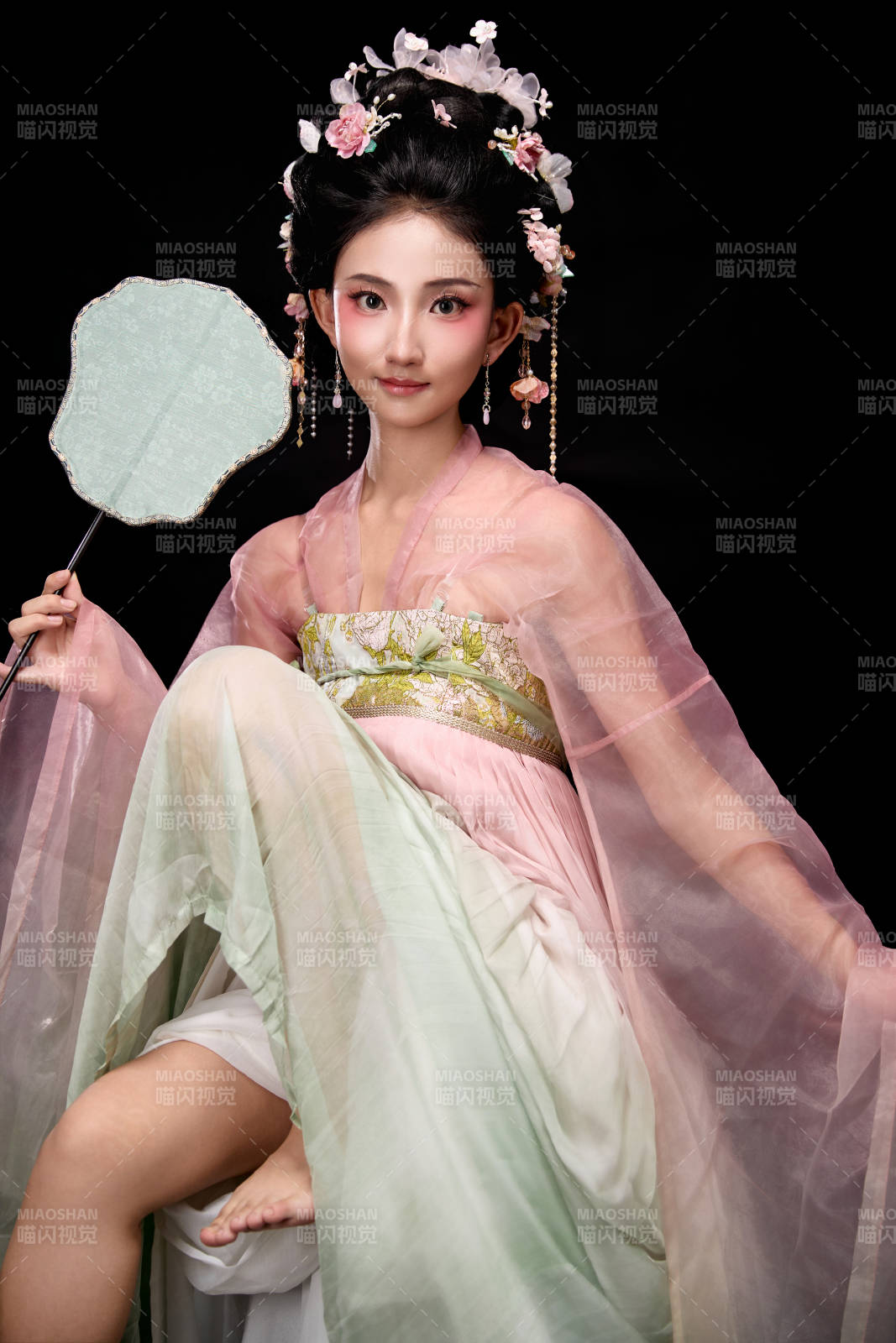 身著唐代簪花仕女服手持輕扇的坐姿女性