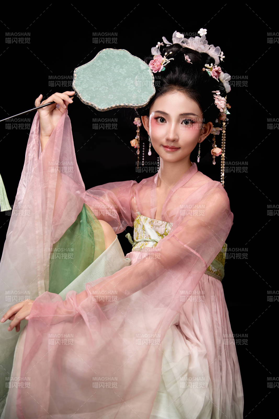 身著唐代簪花仕女服手持輕扇的坐姿女性