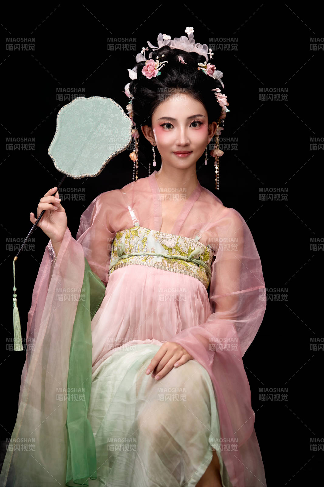 身著唐代簪花仕女服手持輕扇的坐姿女性