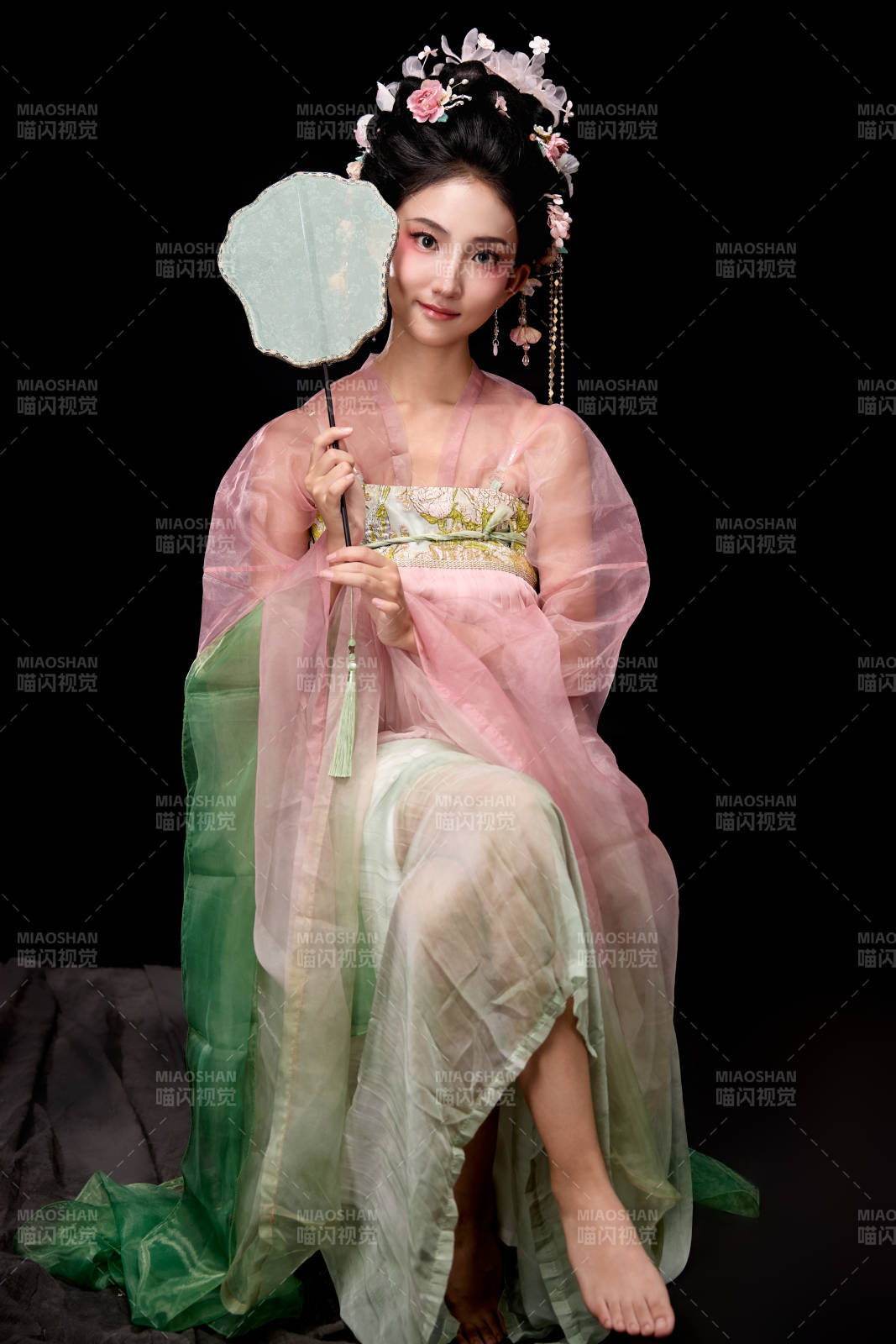 身著唐代簪花仕女服手持輕扇的坐姿女性