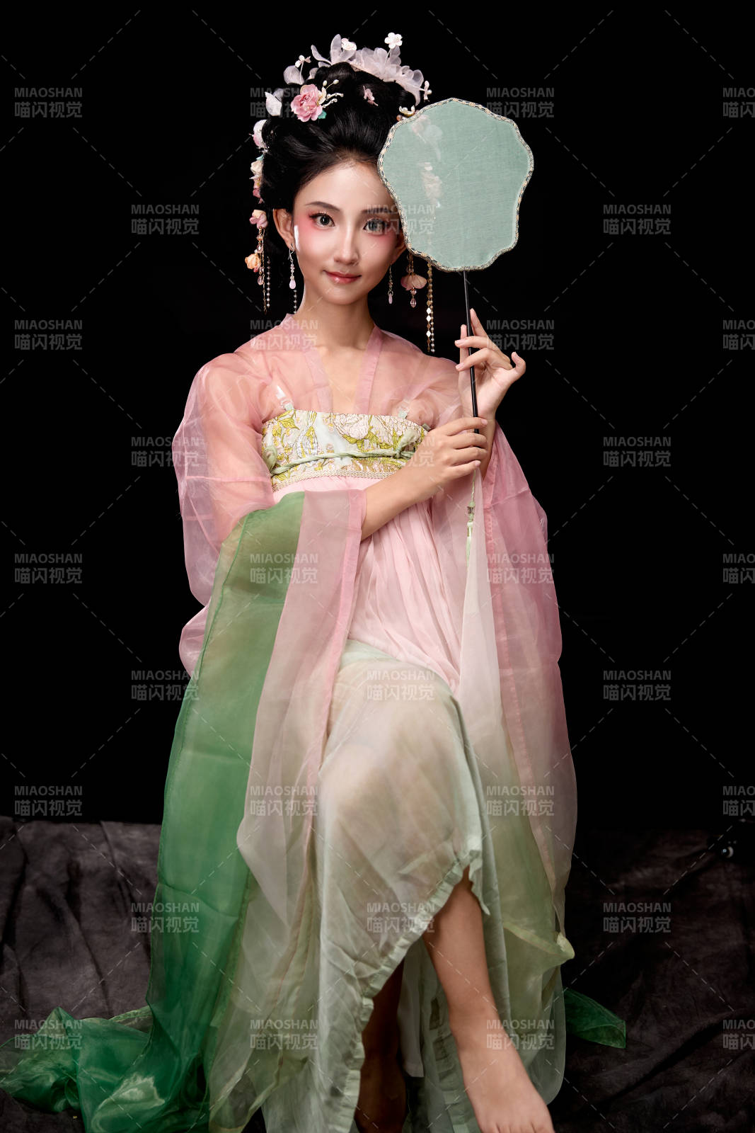 身著唐代簪花仕女服手持輕扇的坐姿女性