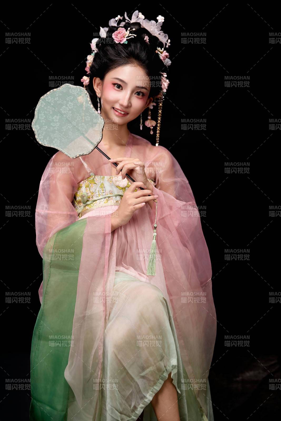 身著唐代簪花仕女服手持輕扇的坐姿女性