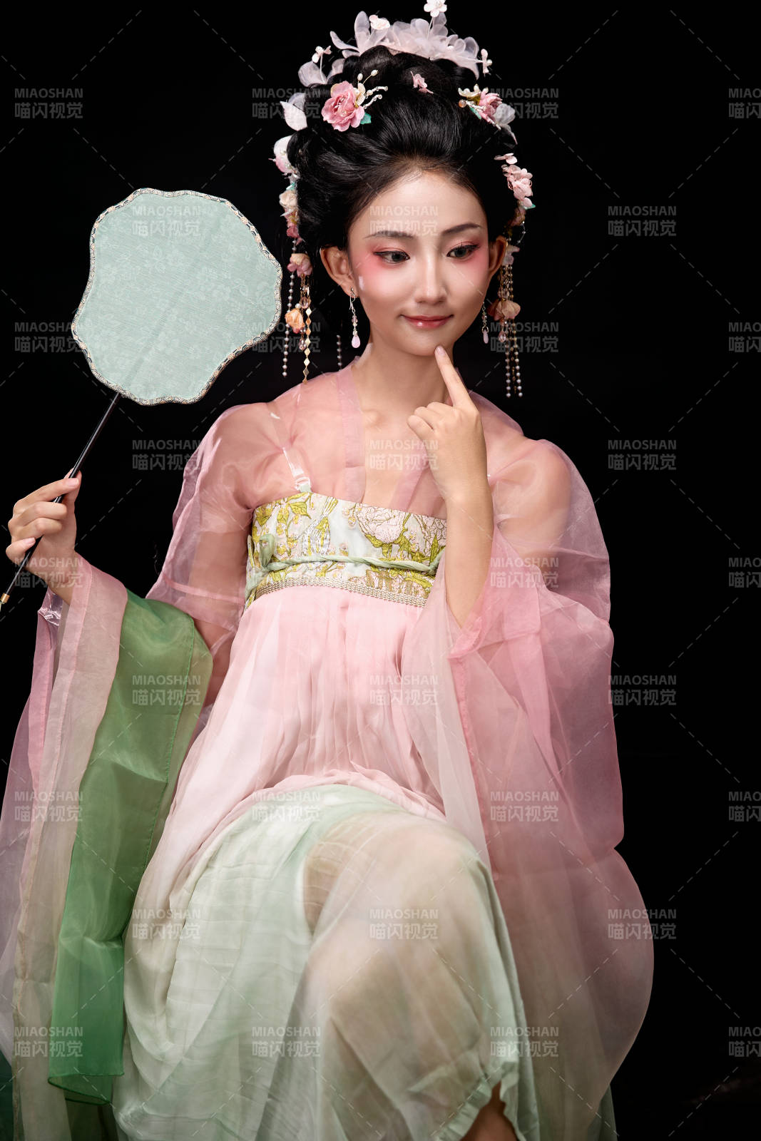 身著唐代簪花仕女服手持輕扇的坐姿女性