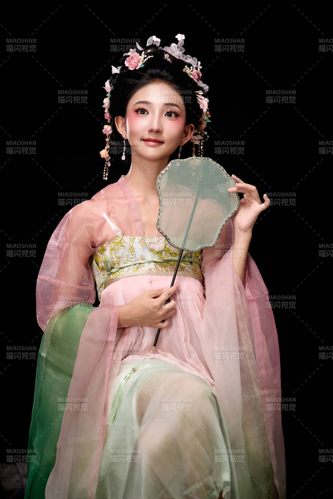 身著唐代簪花仕女服手持輕扇的坐姿女性