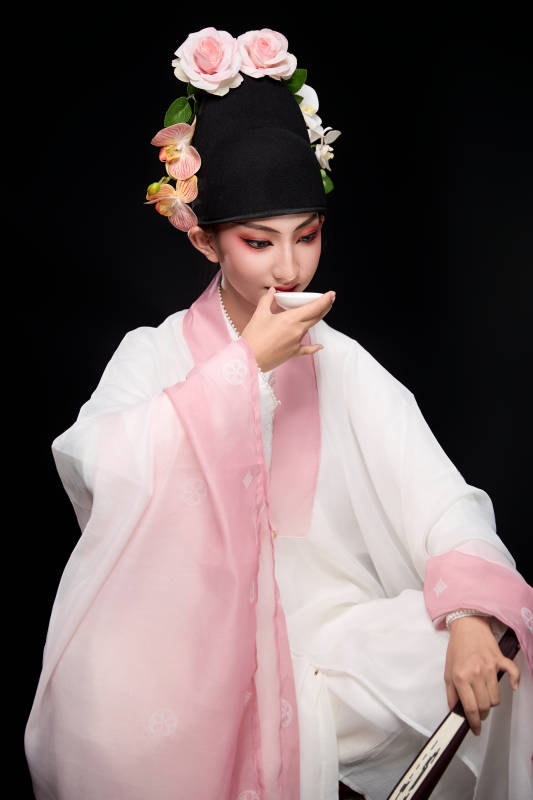 身着粤剧反串装扮手持酒杯折扇的青年女性