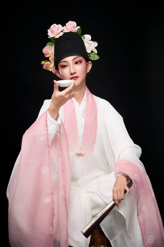 身着粤剧反串装扮手持酒杯折扇的青年女性