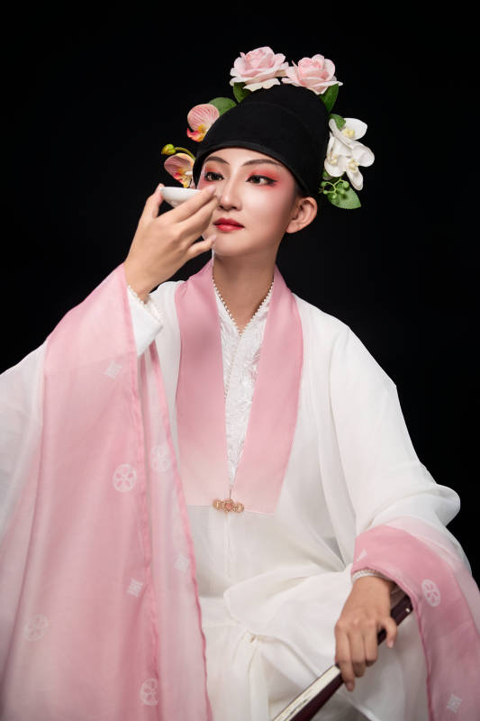 身着粤剧反串装扮手持酒杯折扇的青年女性