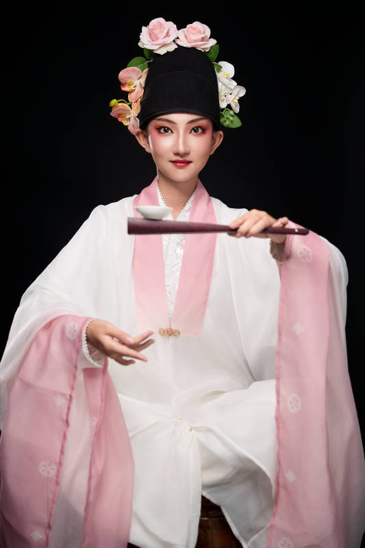 身着粤剧反串装扮手持酒杯折扇的青年女性