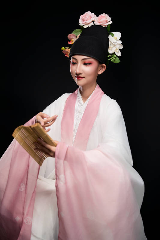 身着粤剧戏曲反串装扮手持竹简的青年女性