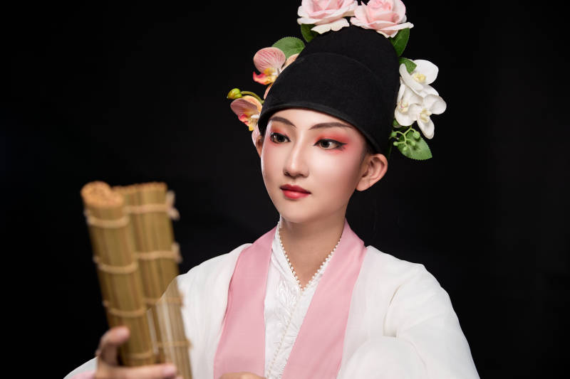 身着粤剧戏曲反串装扮手持竹简的青年女性