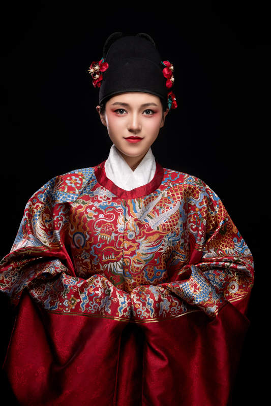 黑色背景下身着明代飞鱼服的青年女性