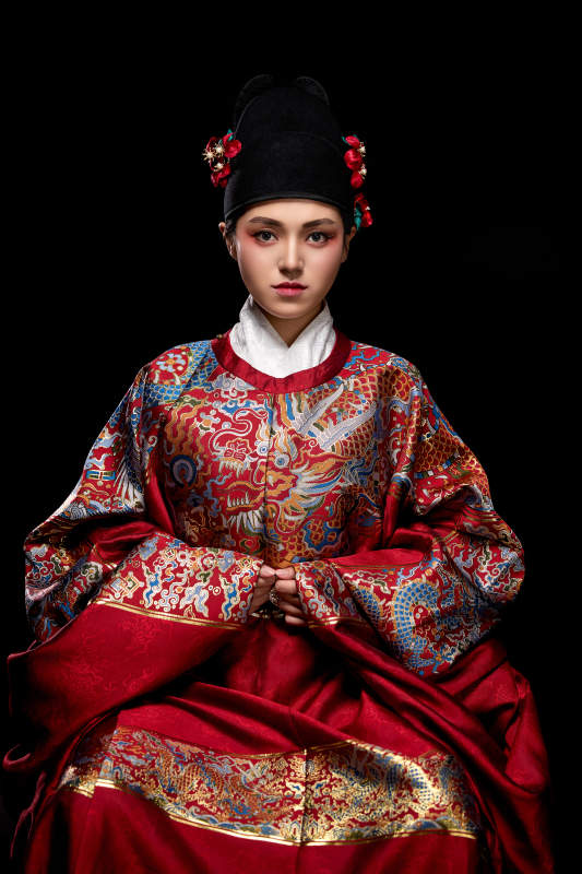 黑色背景下身着明代飞鱼服的青年女性