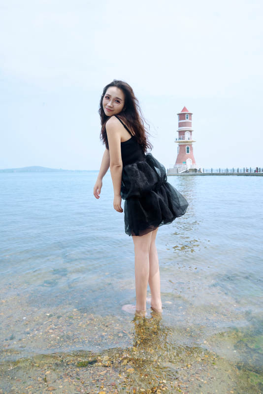 在草原湖畔戏水游玩拍照的亚洲美女