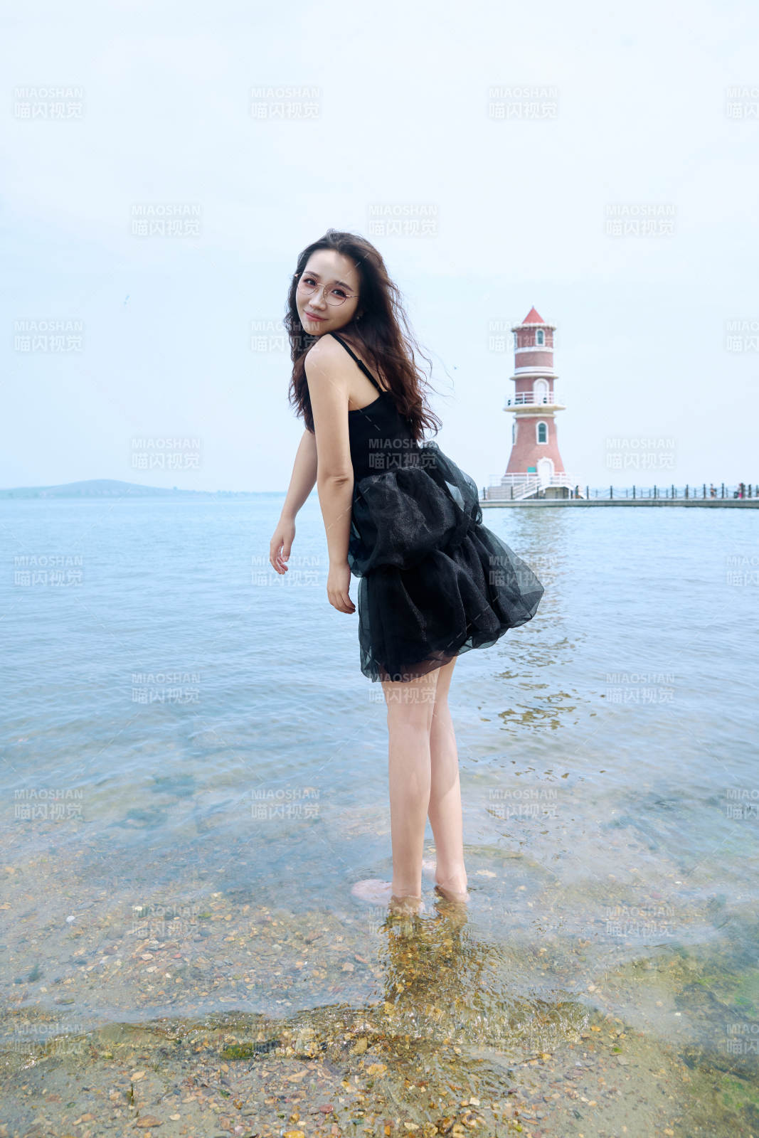 在草原湖畔戏水游玩拍照的亚洲美女