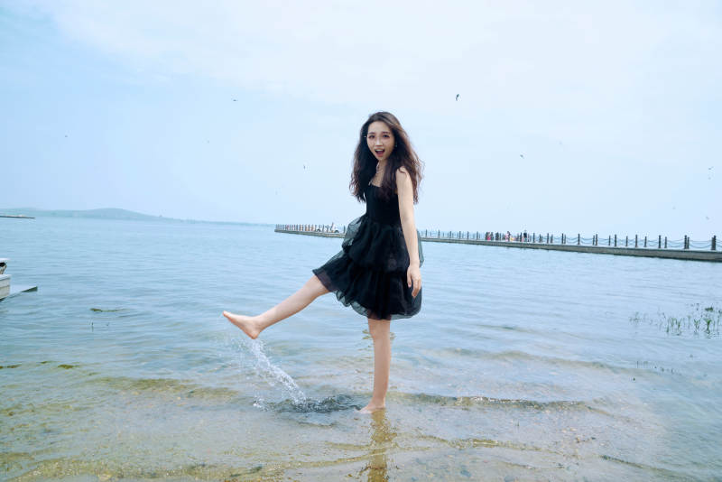 在草原湖畔戏水游玩拍照的亚洲美女