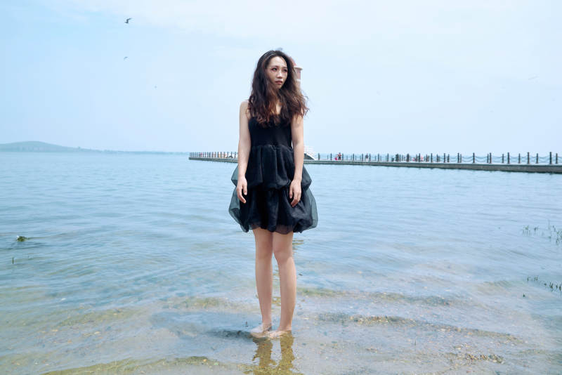 在草原湖畔戏水游玩拍照的亚洲美女