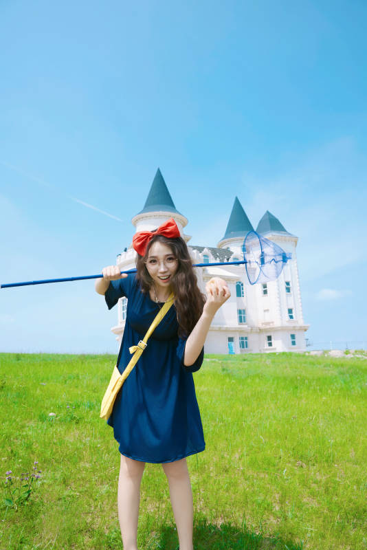 身穿小魔女服饰在城堡前拍照打卡的亚洲美女