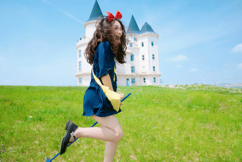 身穿小魔女服饰在城堡前拍照打卡的亚洲美女