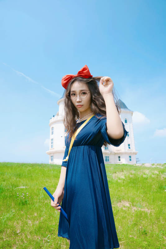 身穿小魔女服饰在城堡前拍照打卡的亚洲美女