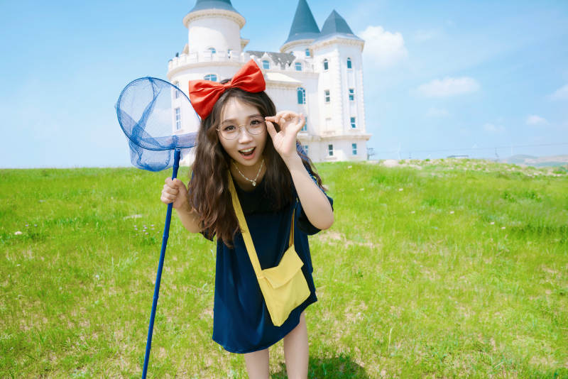 身穿小魔女服饰在城堡前拍照打卡的亚洲美女