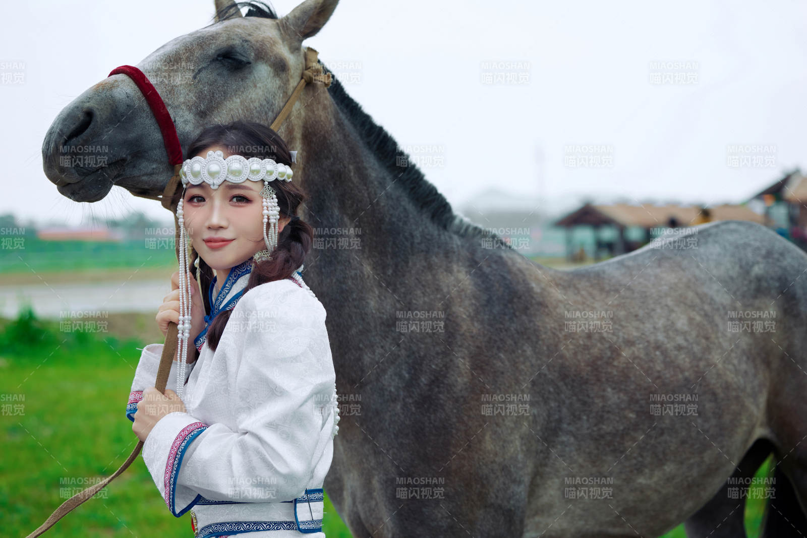 草原上穿著蒙古族服飾牽著馬匹的亞洲美女