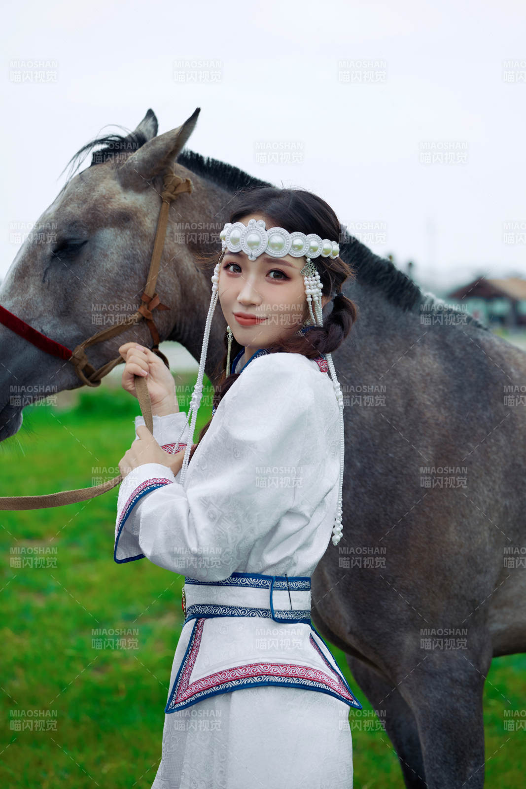 草原上穿著蒙古族服飾牽著馬匹的亞洲美女