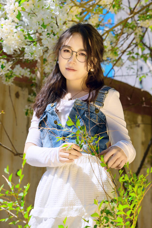 春天在梨花树下拍照的东方美女