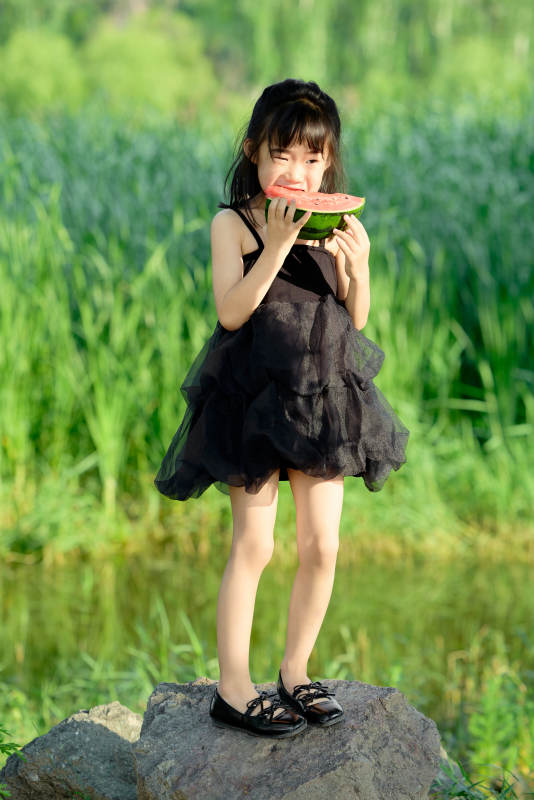 夏季在户外游玩吃西瓜的可爱亚洲女童