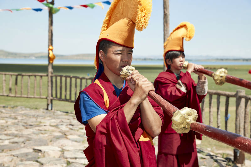 在敖包上吹响铜号的喇嘛僧人