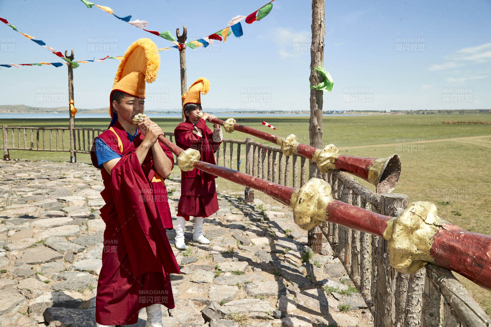 在敖包上吹响铜号的喇嘛僧人