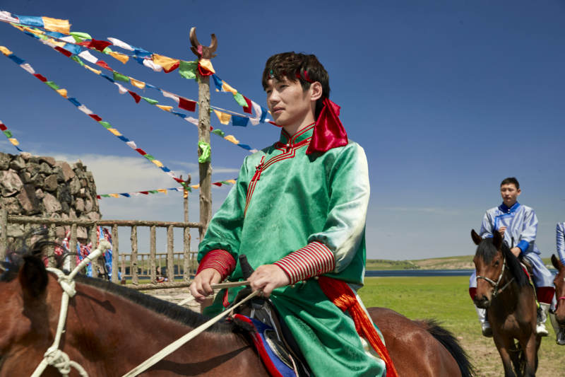 草原那达慕大会上骑着马的蒙古演员