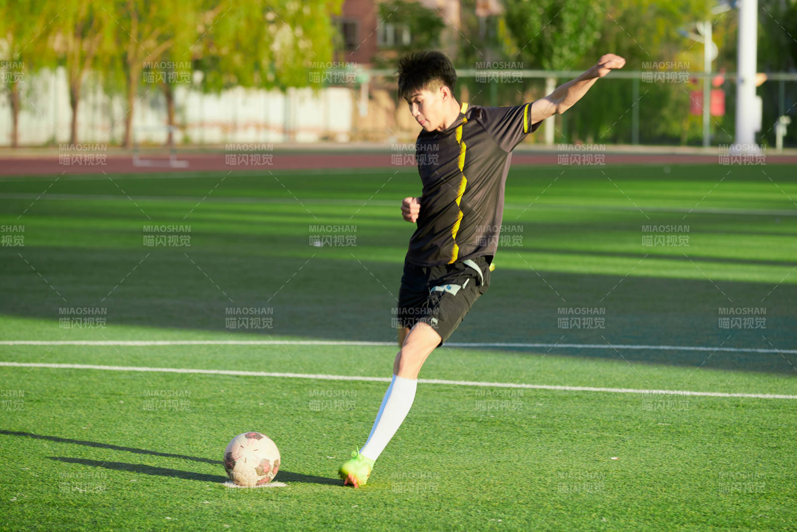戶外足球場上踢足球的運動員