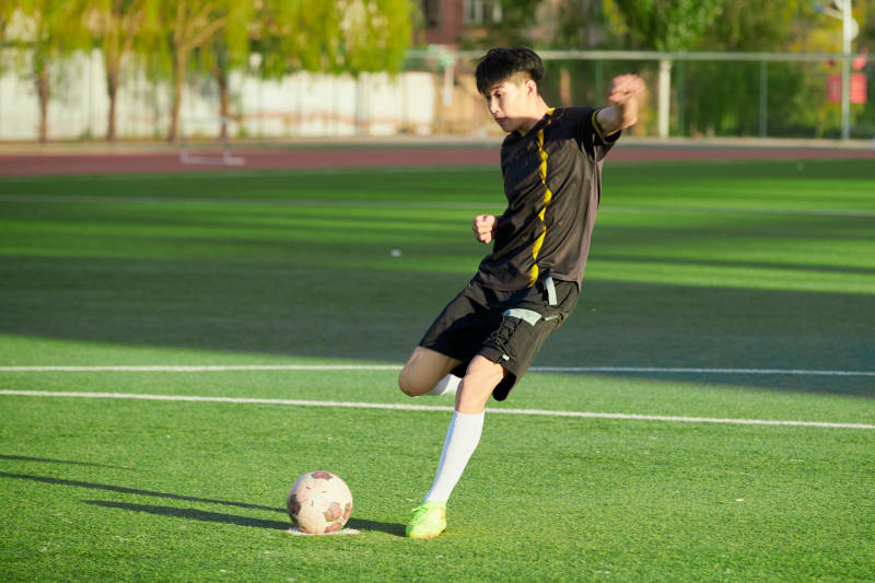 户外足球场上踢足球的运动员