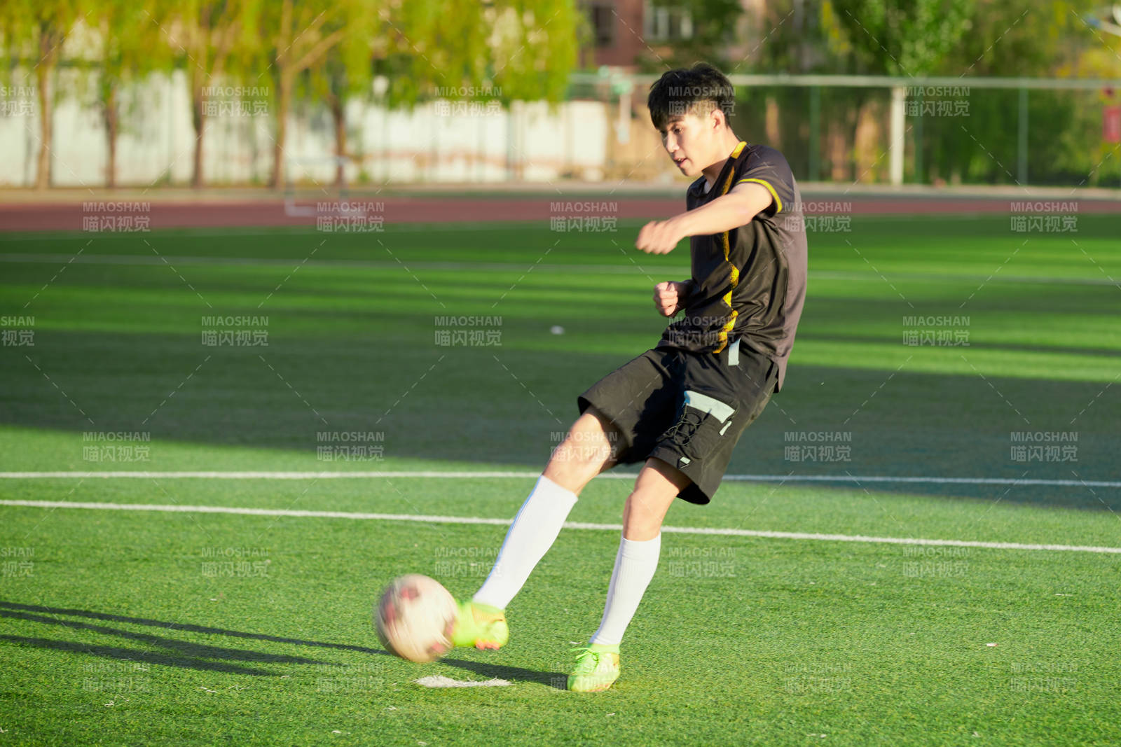 戶外足球場上踢足球的運動員