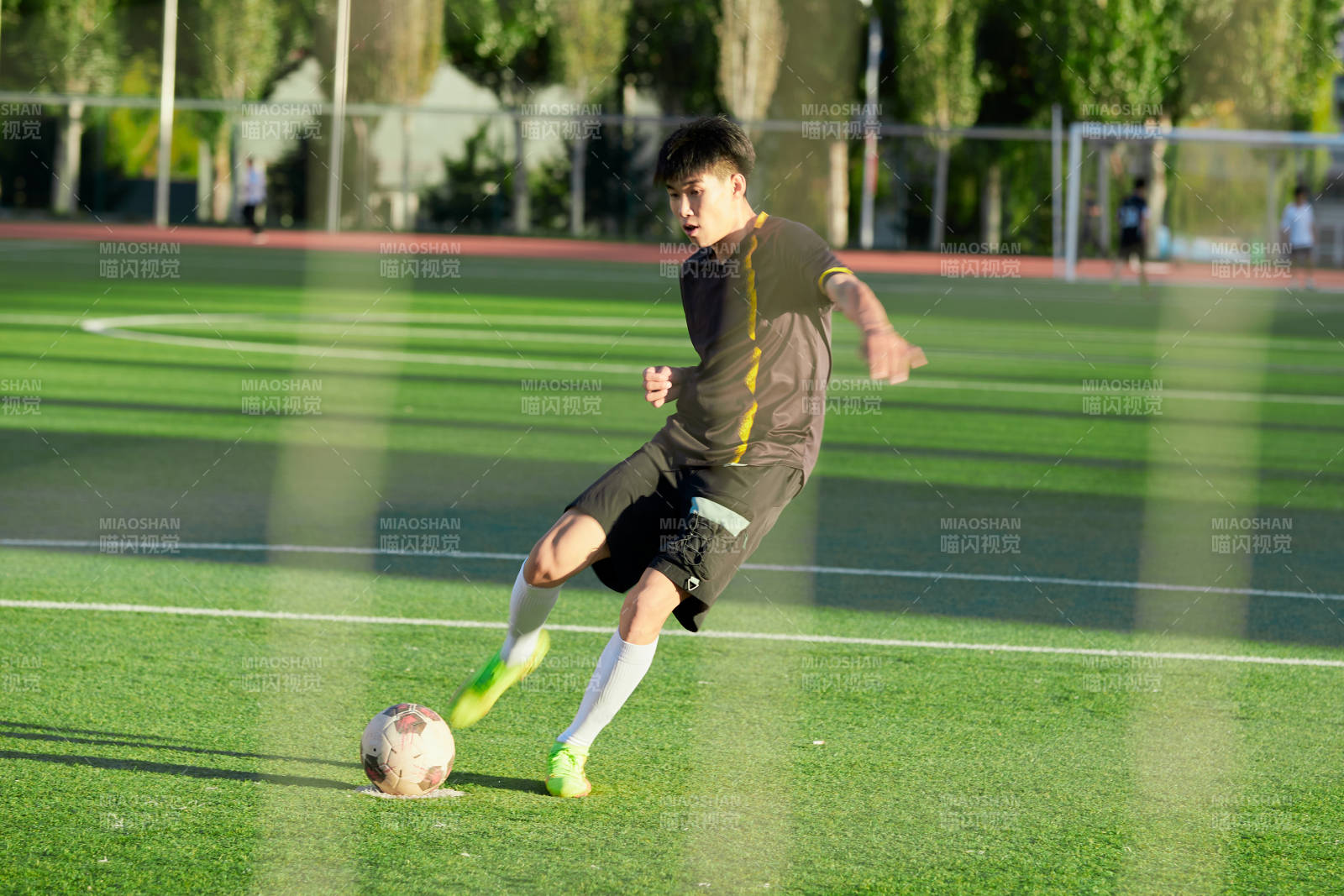 戶外足球場上踢足球的運動員