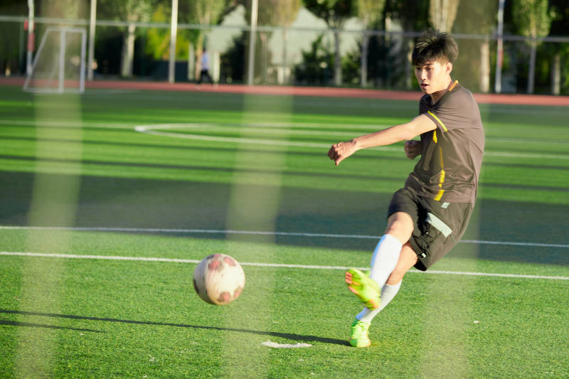 户外足球场上踢足球的运动员