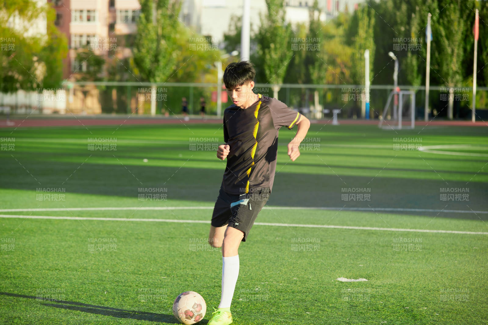 戶外足球場上踢足球的運動員