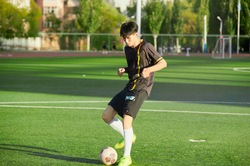 户外足球场上踢足球的运动员