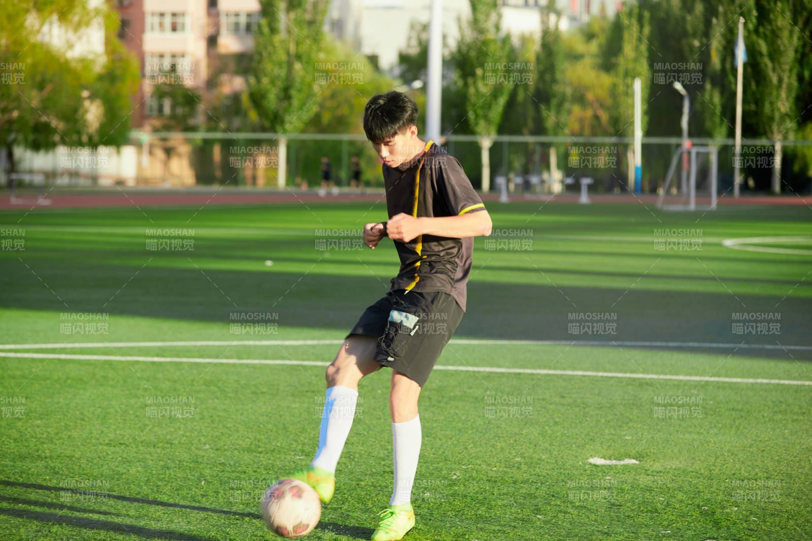 戶外足球場上踢足球的運動員