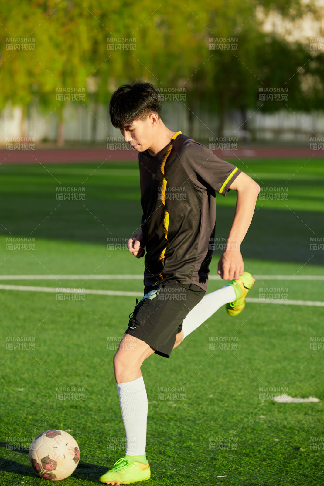 戶外足球場上踢足球的運動員