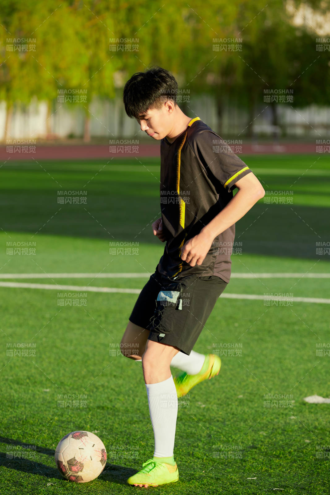 戶外足球場(chǎng)上踢足球的運(yùn)動(dòng)員