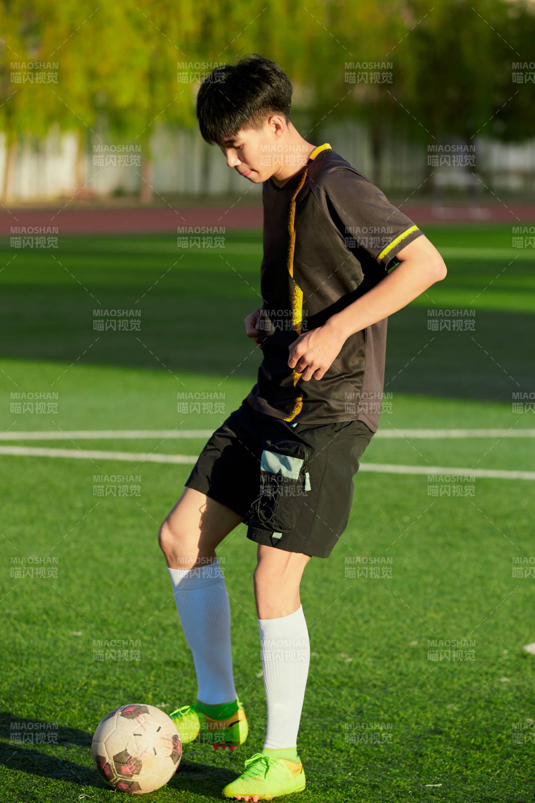 戶外足球場(chǎng)上踢足球的運(yùn)動(dòng)員