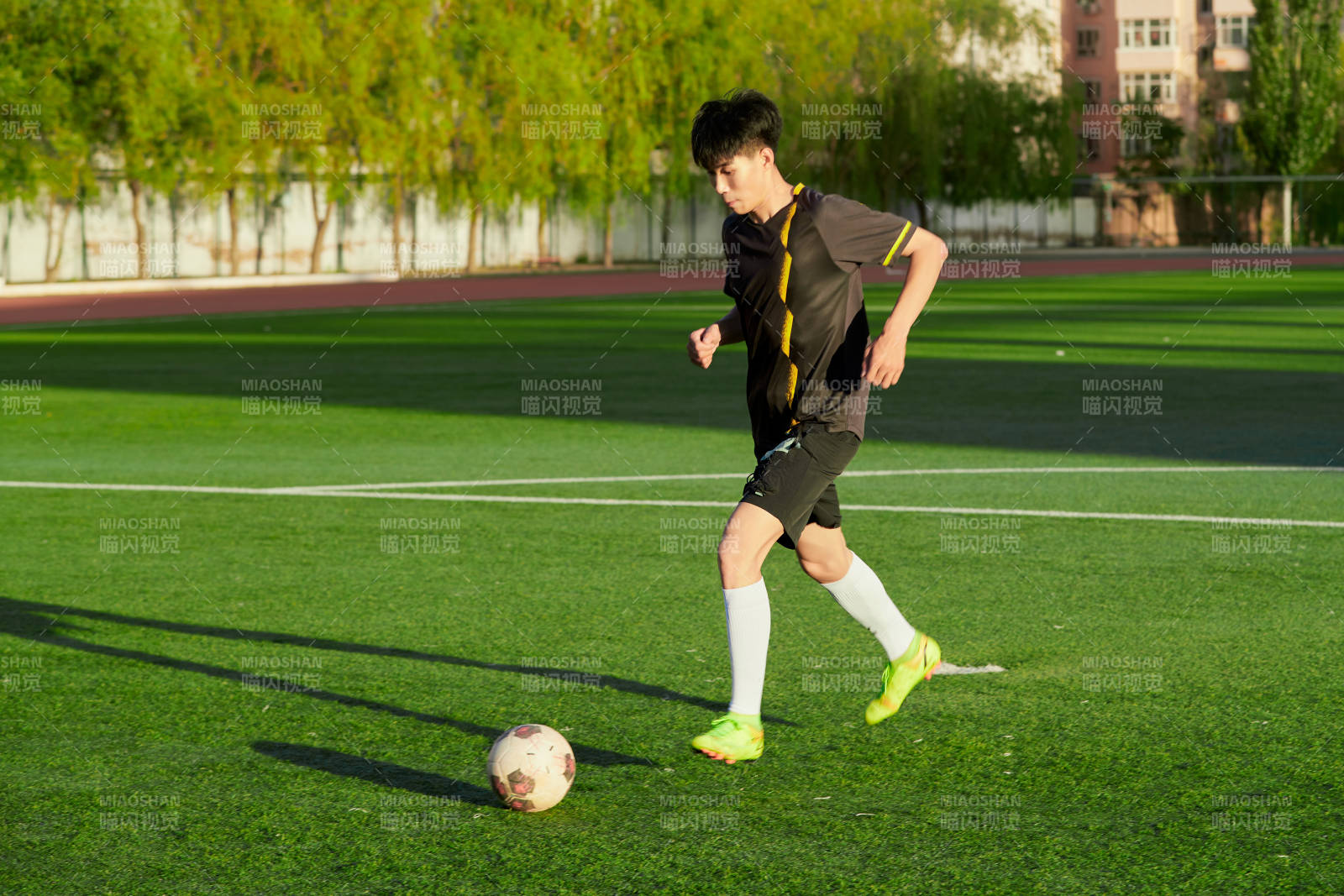 戶外足球場上踢足球的運動員
