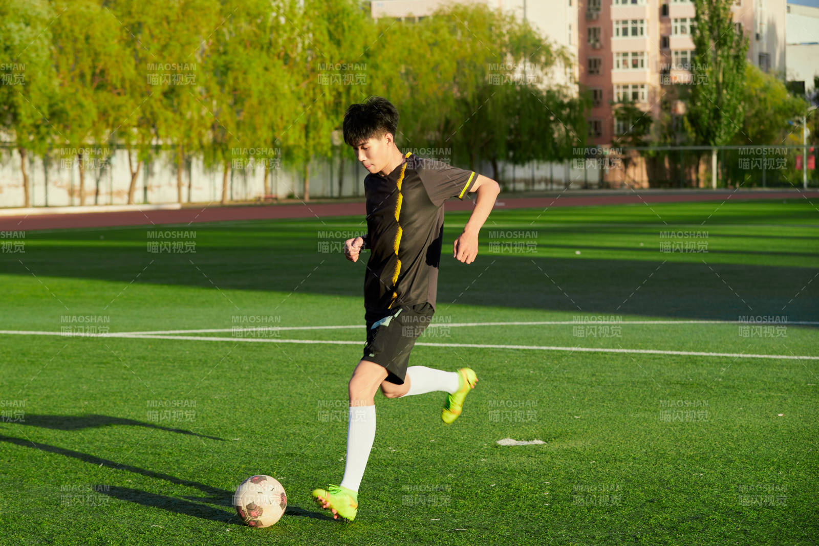 戶外足球場上踢足球的運動員