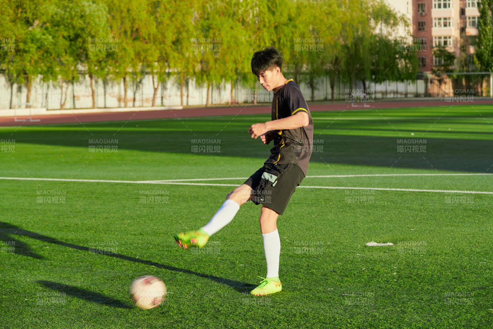 戶外足球場(chǎng)上踢足球的運(yùn)動(dòng)員