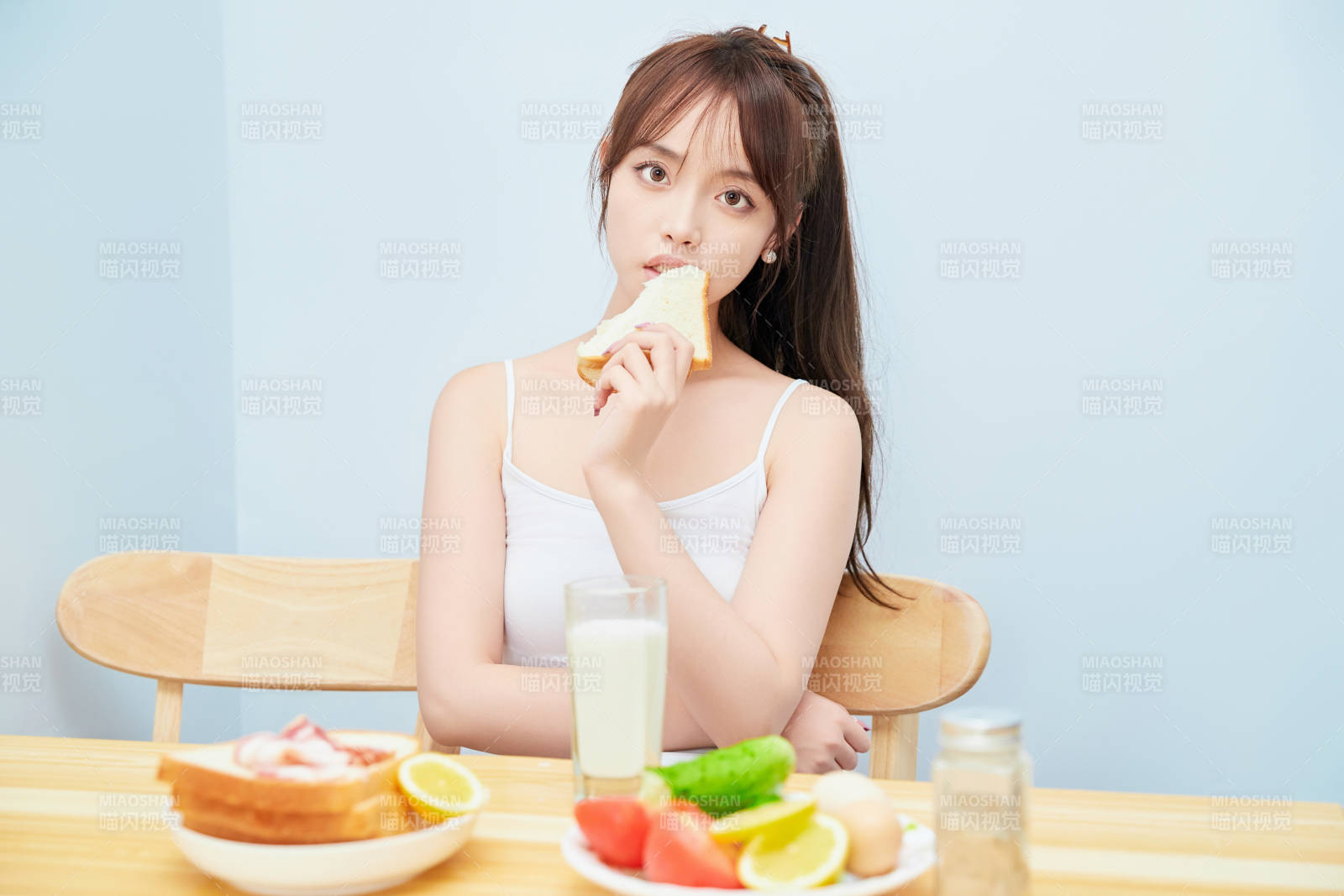 美丽的少女在餐桌前吃早餐