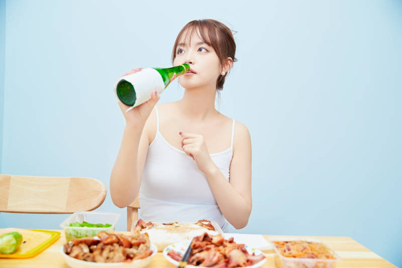 在餐桌前吃午餐喝白酒的亚洲少女