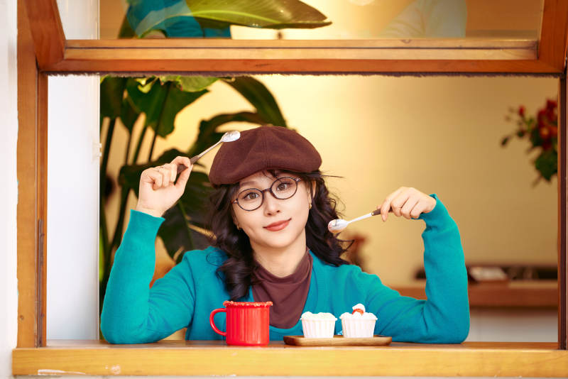 冬日午后坐在咖啡店吃蛋糕喝咖啡的亚洲美女