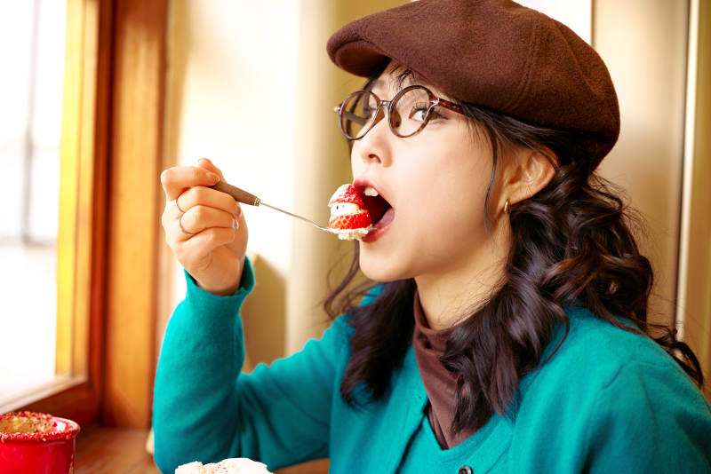 冬日午后坐在咖啡店吃蛋糕喝咖啡的亚洲美女